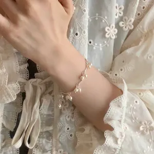 Vista de detalle de una delicada pulsera de perlas minimalista en una muñeca con encaje
