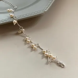 Detalle de cerca de una elegante pulsera de cadena plateada con delicadas perlas colgantes