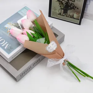 Détail d'un bouquet de tulipes roses dans du papier brun avec un nœud en dentelle