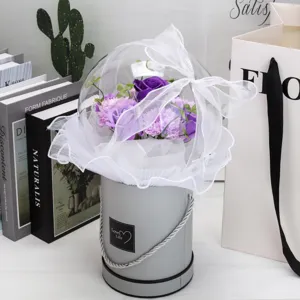 Détail d'un bouquet de roses de savon mauves dans une boîte cadeau sphérique en acrylique.