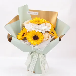 Vista detallada de un ramo de girasoles artificiales y rosas de jabón blancas en papel.