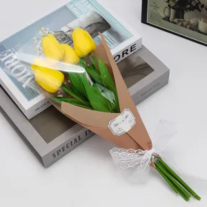 Bouquet de tulipes jaunes artificielles emballé dans du papier kraft et de la dentelle blanche