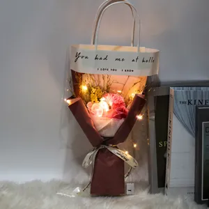 Ramo de flores de jabón rosa con luces LED cálidas en una bolsa de regalo transparente asa