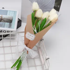 Vue détaillée d'un bouquet de tulipes artificielles crème enveloppé dans du papier brun et dentelle