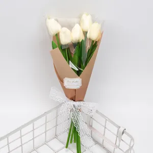 Élégant bouquet de tulipes blanches artificielles enveloppé dans du papier brun avec dentelle