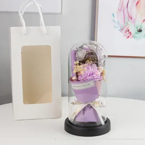 Eternal flower glass dome detail showing purple dried carnation bouquet and warm LED string lights.
