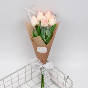 Bouquet de tulipes roses artificielles dans un emballage en papier avec un nœud