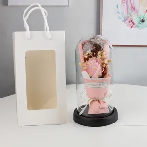 Detailed view of eternal rose glass dome with fairy lights and pink gift bag for lovers.