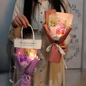 Primer plano de ramos de flores de jabón con luces LED para regalo ideal en las manos.
