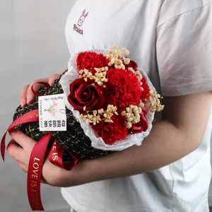 Dettaglio di un bouquet di fiori di sapone con garofani rossi e involucro in tweed