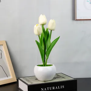 Primer plano detallado de tulipanes blancos artificiales en maceta de cerámica sobre libro.