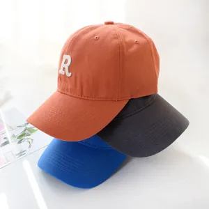 Close-up view of three stacked cotton baseball caps in orange gray and blue colors