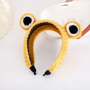 Detailed view of the cute yellow knitted frog eye hair hoop, soft wool texture close up.