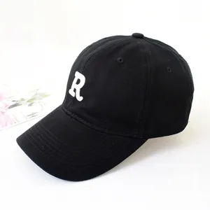 Close-up detail of a black cotton baseball cap with an embroidered white letter R