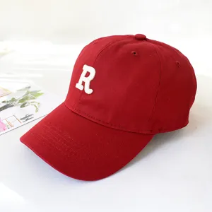 Close-up detail of a red cotton baseball cap with a white embroidered R letter