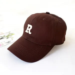 Detailed close-up of a brown cotton baseball cap featuring a white embroidered R letter