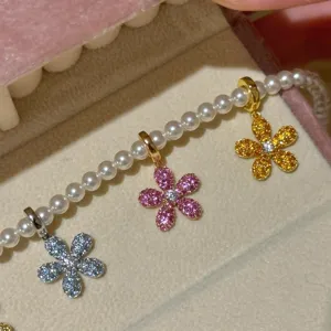 Detailed macro view of sparkling colorful zircon daisy pendants on a pearl chain.
