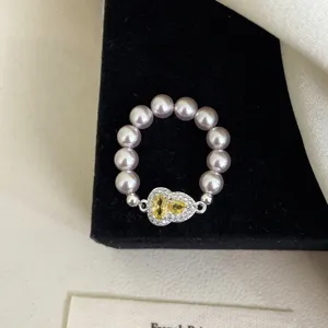Primer plano de un elegante anillo con forma de calabaza, perlas rosas y circón amarillo