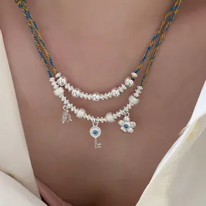 Dettaglio di una collana a doppio strato vintage con ciondoli a chiave e fiore d'argento.