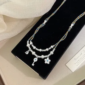 Primo piano della collana retrò a doppio strato con chiave e fiore di diamante