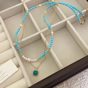 Dettaglio collana a strati con perle d'acqua dolce e ciondolo turchese quadrato