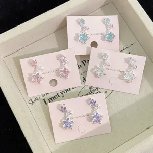Detail of star-shaped earrings with colorful cubic zirconia displayed on pink cards