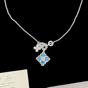 Detail view of silver necklace featuring blue zircon flower pendant and pearl accents