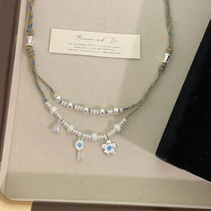 Dettaglio della collana etnica a doppio strato con ciondoli a fiore blu e chiave
