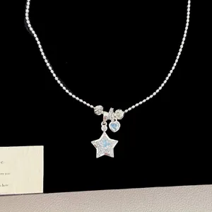 Close-up of silver star and heart necklace charms with sparkling blue zircons and crystals.