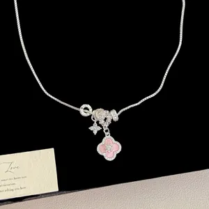 Detailed macro view of silver necklace with pink clover pendant and sparkling zirconia stars