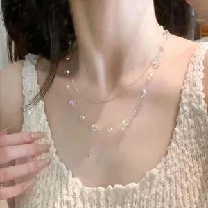 Close-up view of a sweet iridescent crystal ball layered necklace on a model's neck
