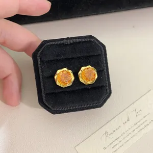 Primer plano elegante de pendientes de circonita ámbar en una caja de terciopelo negro.