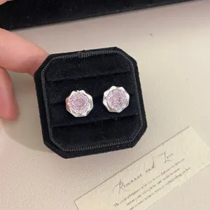 Primer plano de pendientes de circonita rosa con talla de rosa en caja de regalo.