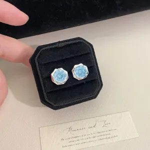 Detalle de pendientes brillantes de circonita azul claro en caja de terciopelo negro.