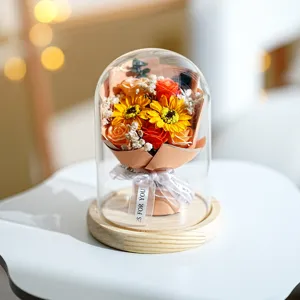 Detailansicht von Sonnenblumen und Rosen in einer Glaskuppel mit echtem Holzsockel.