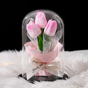 Elegante lámpara de tulipanes rosas en cúpula de vidrio sobre fondo de piel sintética