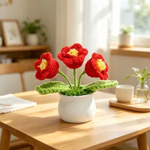Handmade red crochet flowers in a white pot on a wooden table under natural sunlight.