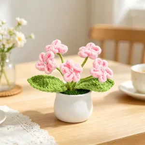 Close-up of handmade pink crochet flower pot with pearl details and ceramic base