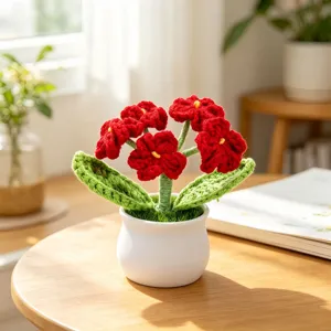 Detail view of handmade crochet potted flower with red petals and a white ceramic pot