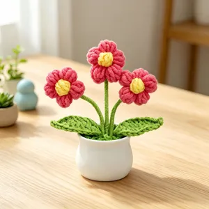 Hand-knitted pink flower potted plant with white ceramic pot on desk