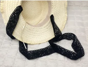 Close-up detail view of a women's straw sun hat with elegant black lace ribbon strap