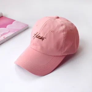 Close-up of pink embroidered baseball cap with soft crown and stylish holiday text detail.