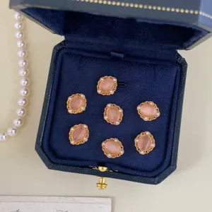 Vintage peach cat-eye stone buttons with gold filigree and pearls in a navy blue jewelry box.
