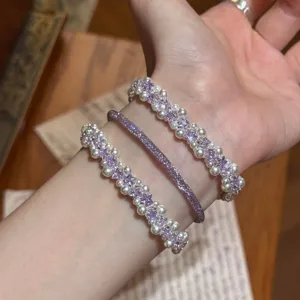 Vista detallada de un conjunto de pulseras de circonitas púrpuras y perlas blancas