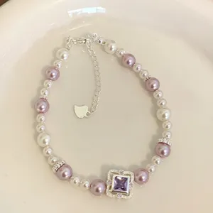 Detailed macro view of an elegant purple and white pearl bracelet with a square gemstone