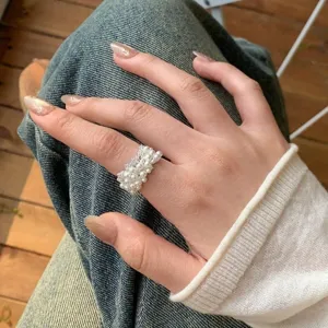 Lifestyle-Detail eines breiten, verstellbaren Rings mit weißen Perlen am Zeigefinger.