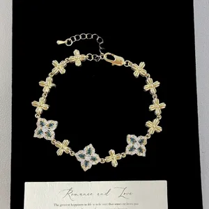 Close-up of vintage French style gold bracelet with green four-leaf clover motifs