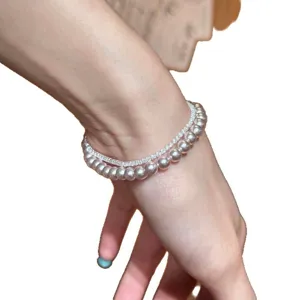 Elegante pulsera de doble capa con perlas y circonitas para mujer mostrada en la muñeca