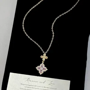 Detailed view of a luxury gold necklace with a purple four-leaf flower pendant on black velvet