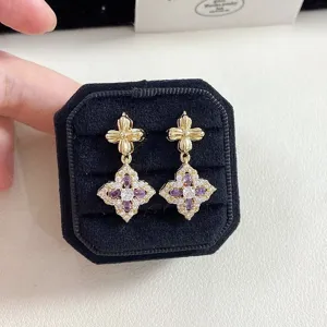 Detailed macro shot of vintage gold floral earrings set with purple and white stones.